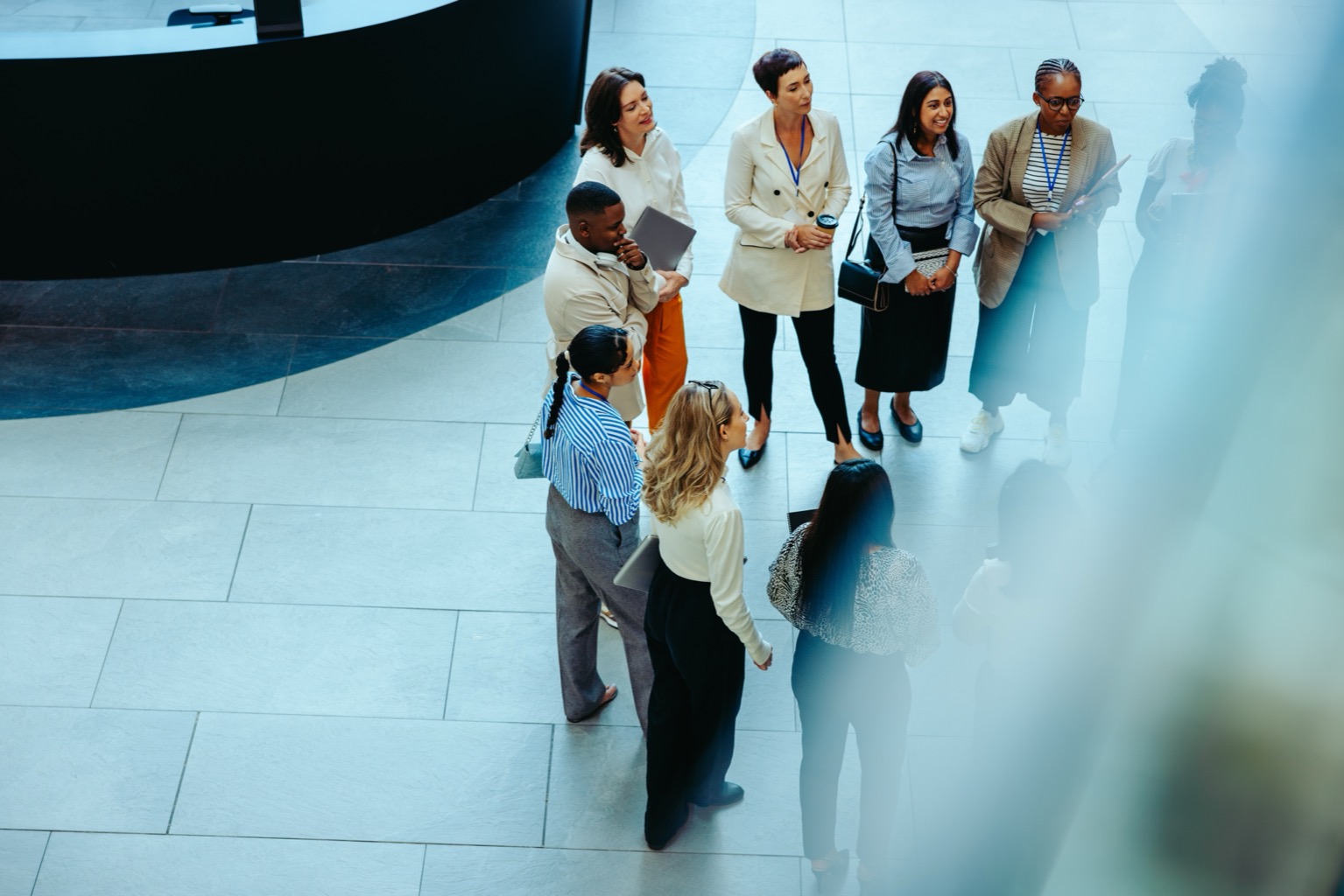 Overhead view of a diverse group of professionals networking with lanyards in a modern office lobby